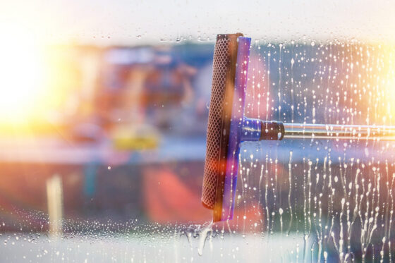 Squeegee wiping water from sunlit window